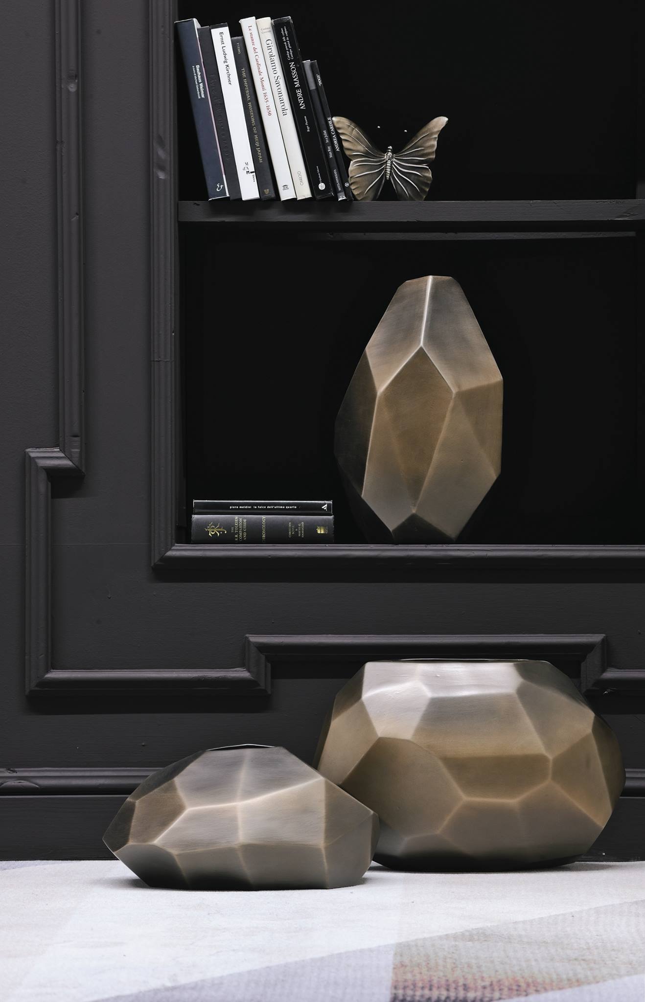 Γλυπτικά, πρισματικά βάζα σε ορειχάλκινο φινίρισμα, σε minimal σύνθεση με βιβλία.