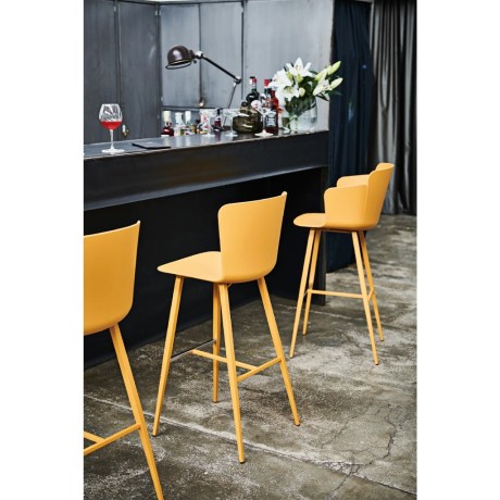 Κίτρινα σκαμπό μπαρ Midj Calla τοποθετημένα σε minimal industrial bar counter ξενοδοχείου.