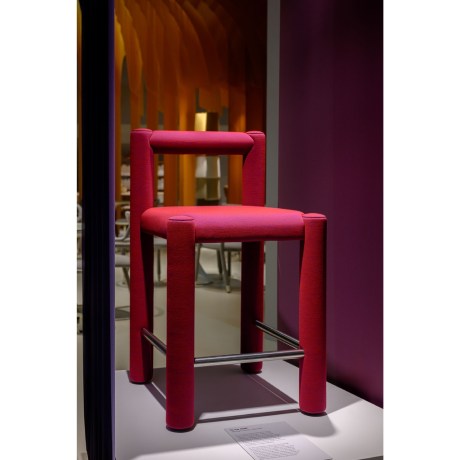 The Midj TU-BE bar stool in fuchsia-red upholstery, showcased in a high-end OIKADE Contract showroom with atmospheric lighting.